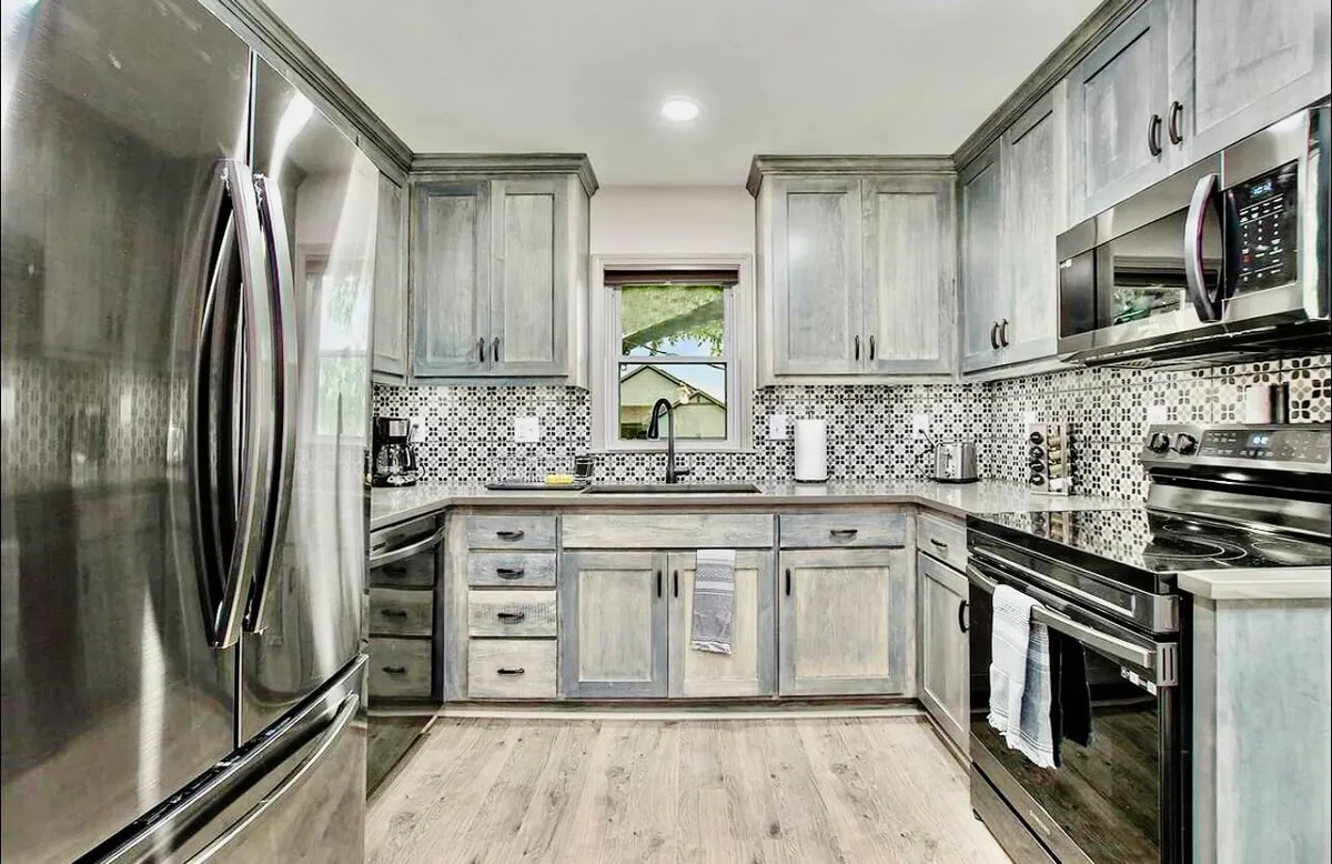 This image features a modern kitchen with stainless steel appliances, a spacious kitchen island, colorful backsplash, and contemporary cabinetry. The area is bright and welcoming, providing ample prep space and a stylish, functional atmosphere ideal for cooking and gathering.
